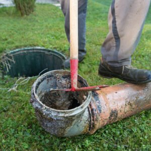 A Rhino Rooter worker clears a clogged outdoor sewer pipe to restore normal flow and prevent future problems.