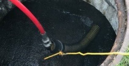 Rhino Rooter is cleaning a drain using special hoses, showing that pipe or sewer work is being done.